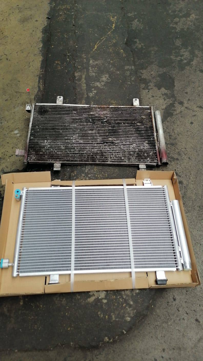 Condensador de aire acondicionado antiguo junto al repuesto nuevo